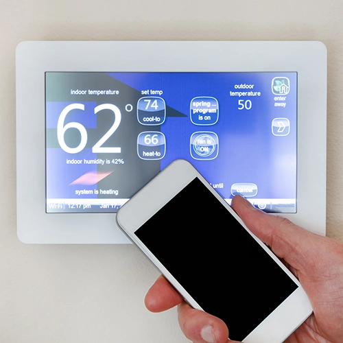 Smart phone held next to a smart heating display unit by an electrician